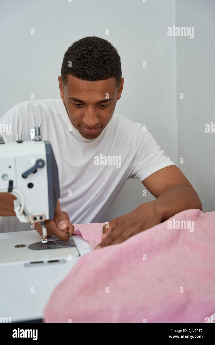 Hombre sonriente disfrutando haciendo ropa en atelier Foto de stock