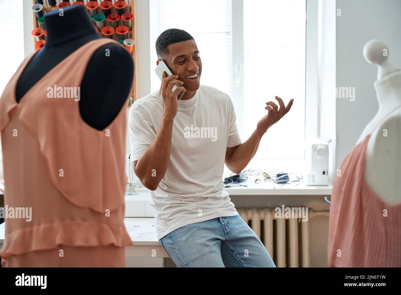 Hombre alegre hablando por teléfono inteligente en la tienda de ropa Foto de stock
