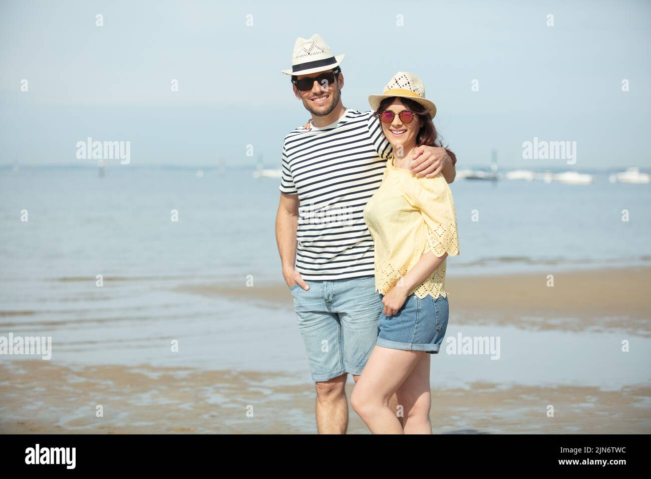 pareja alegre abrazando y posando en la playa Foto de stock