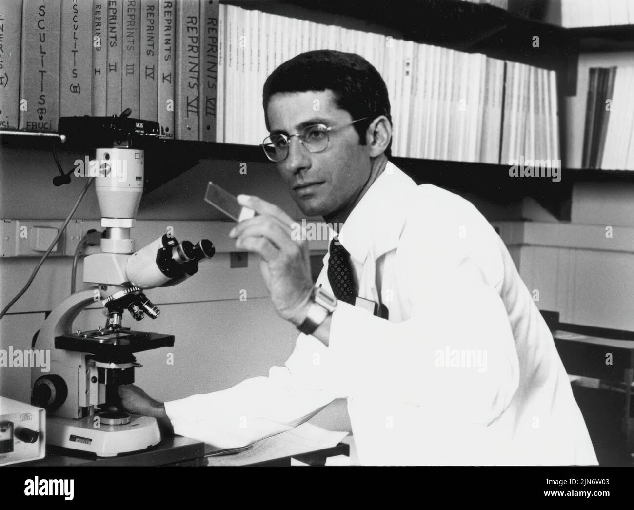 Anthony Fauci, 1984 Dr. Anthony Fauci trabajando al microscopio, 1984. Crédito: NIAID Foto de stock