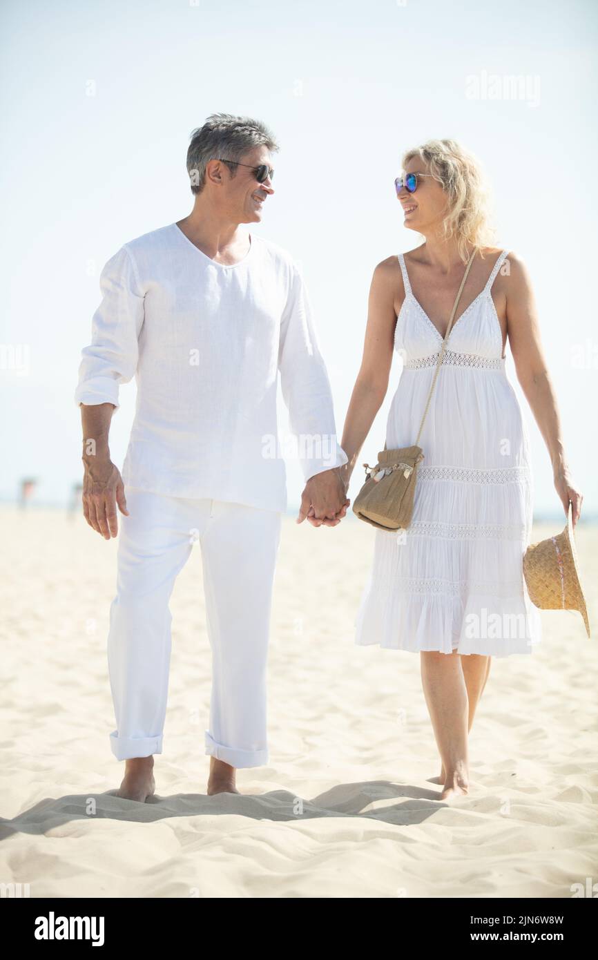 una pareja de mediana edad feliz y romántica disfrutando del paseo por la playa Foto de stock