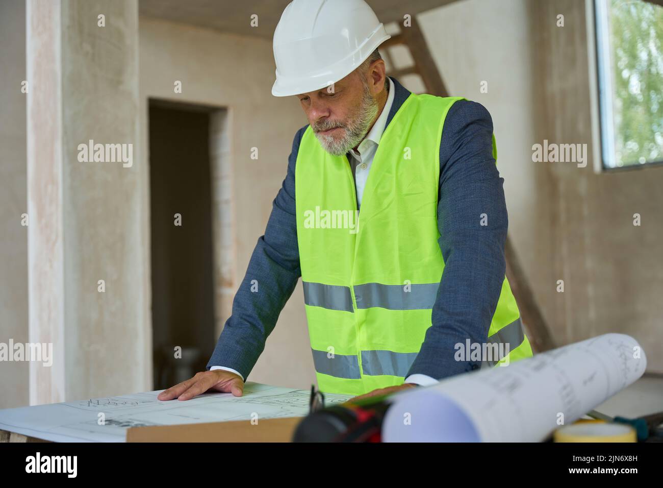 Chaleco de construcción Foreman mira dibujo en la mesa Foto de stock