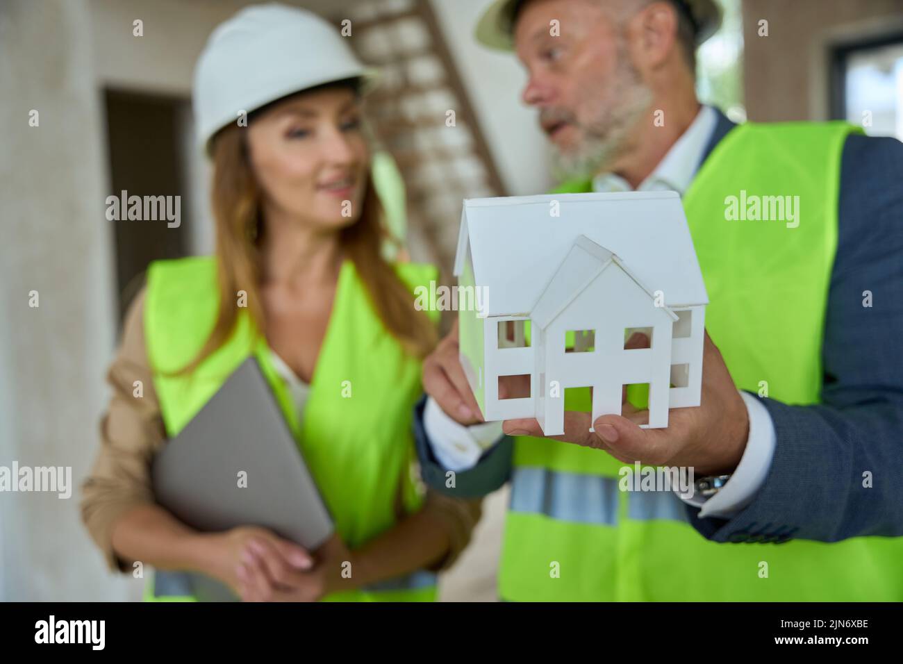 El capataz muestra al agente de bienes raíces un pequeño modelo de casa Foto de stock