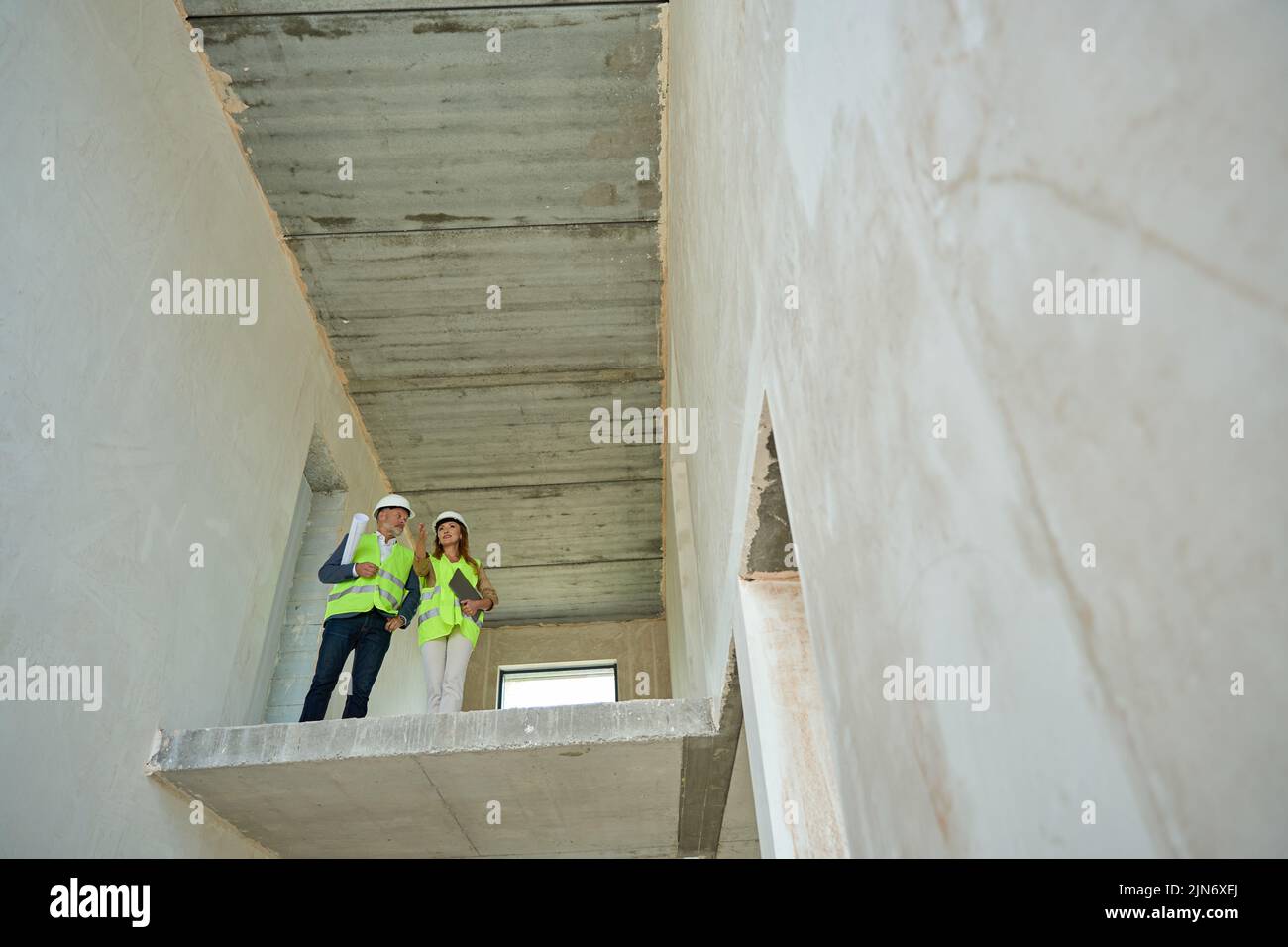 El capataz y el gerente inspeccionan la casa en construcción en el segundo piso Foto de stock