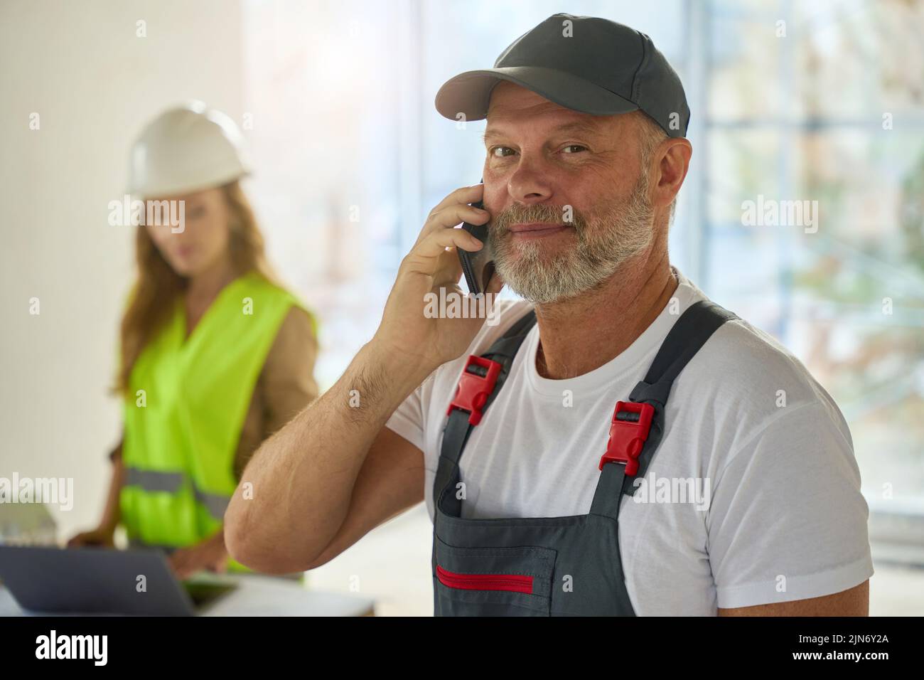 Foto del constructor hablando por teléfono. En el fondo es agente inmobiliario Foto de stock