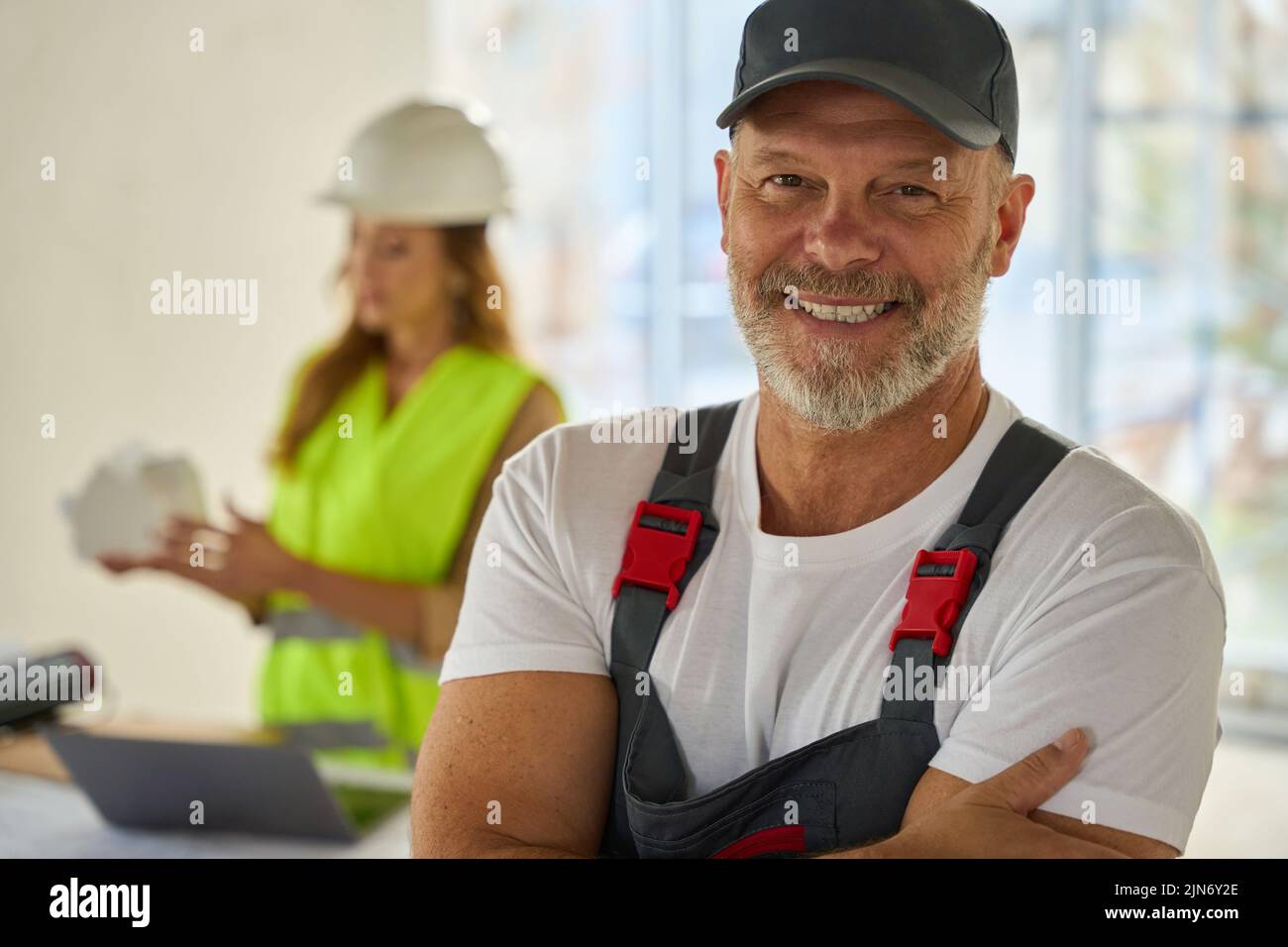 Retrato del constructor sonriente. Detrás está el agente inmobiliario que sostiene la casa modelo Foto de stock