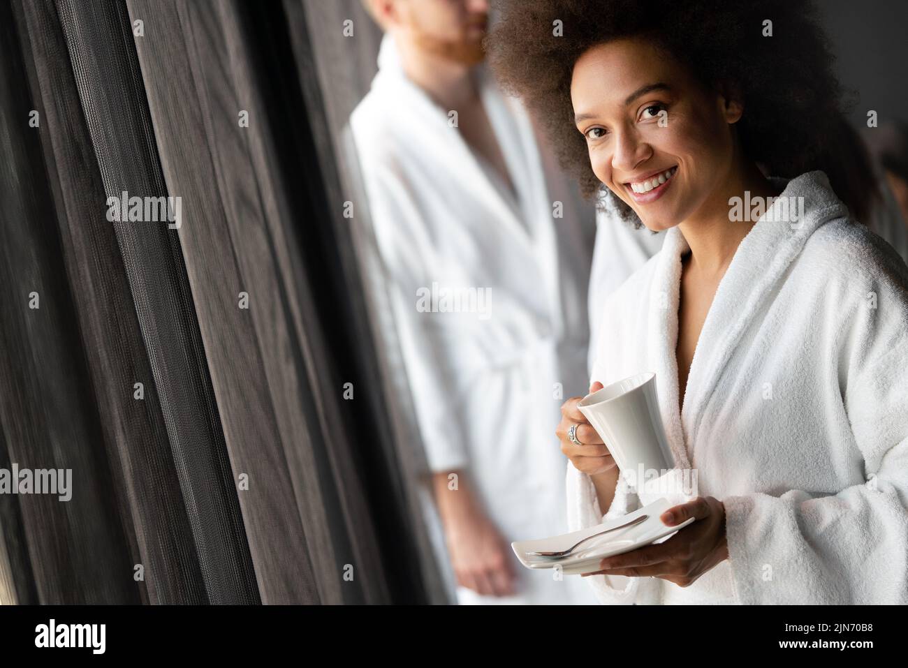 Hermosa mujer negra que se relaja en el spa del hotel de lujo con albornoz y beber café Foto de stock