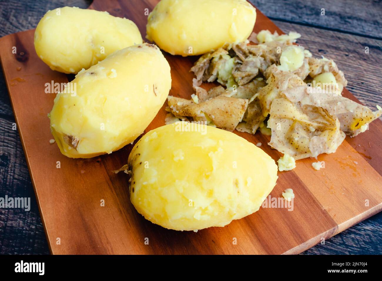 Cortar patatas en tabla de madera con patatas en metal cesta en el fondo  Fotografía de stock - Alamy