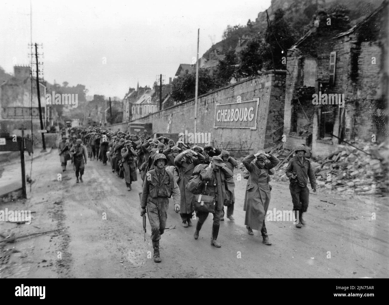 CHERBOURG, FRANCIA - 28 de junio de 1944 - Soldados del Ejército de los EE.UU. marchan a los prisioneros de guerra del ejército alemán fuera de Cherburgo Francia poco después de tomar la ciudad durante la I Normandía Foto de stock