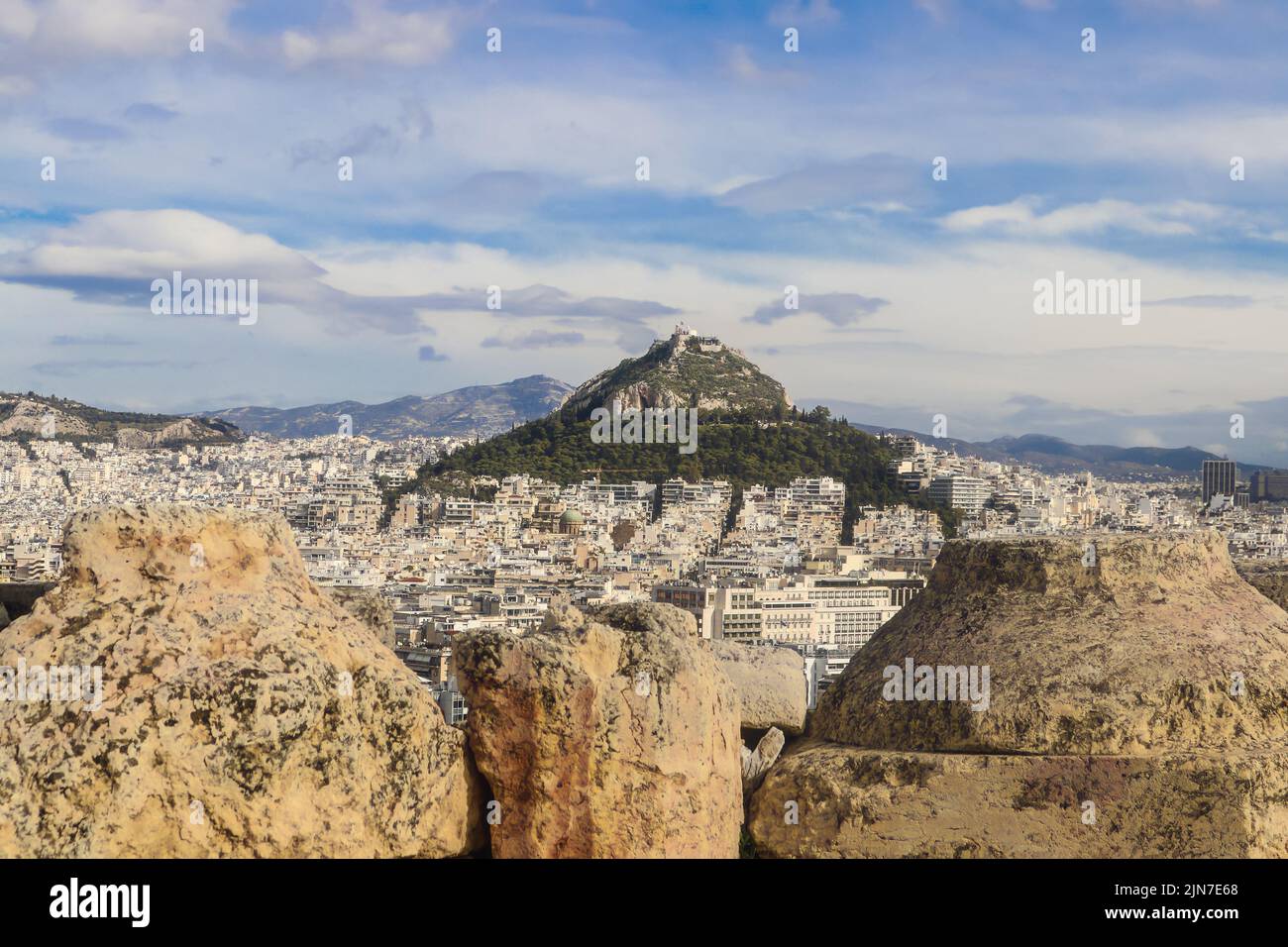 La Capilla Georgios encalada encaramada en la cima de la colina Lykavittos en Atenas, vista desde detrás de las paredes rocosas de la Acrópolis Foto de stock