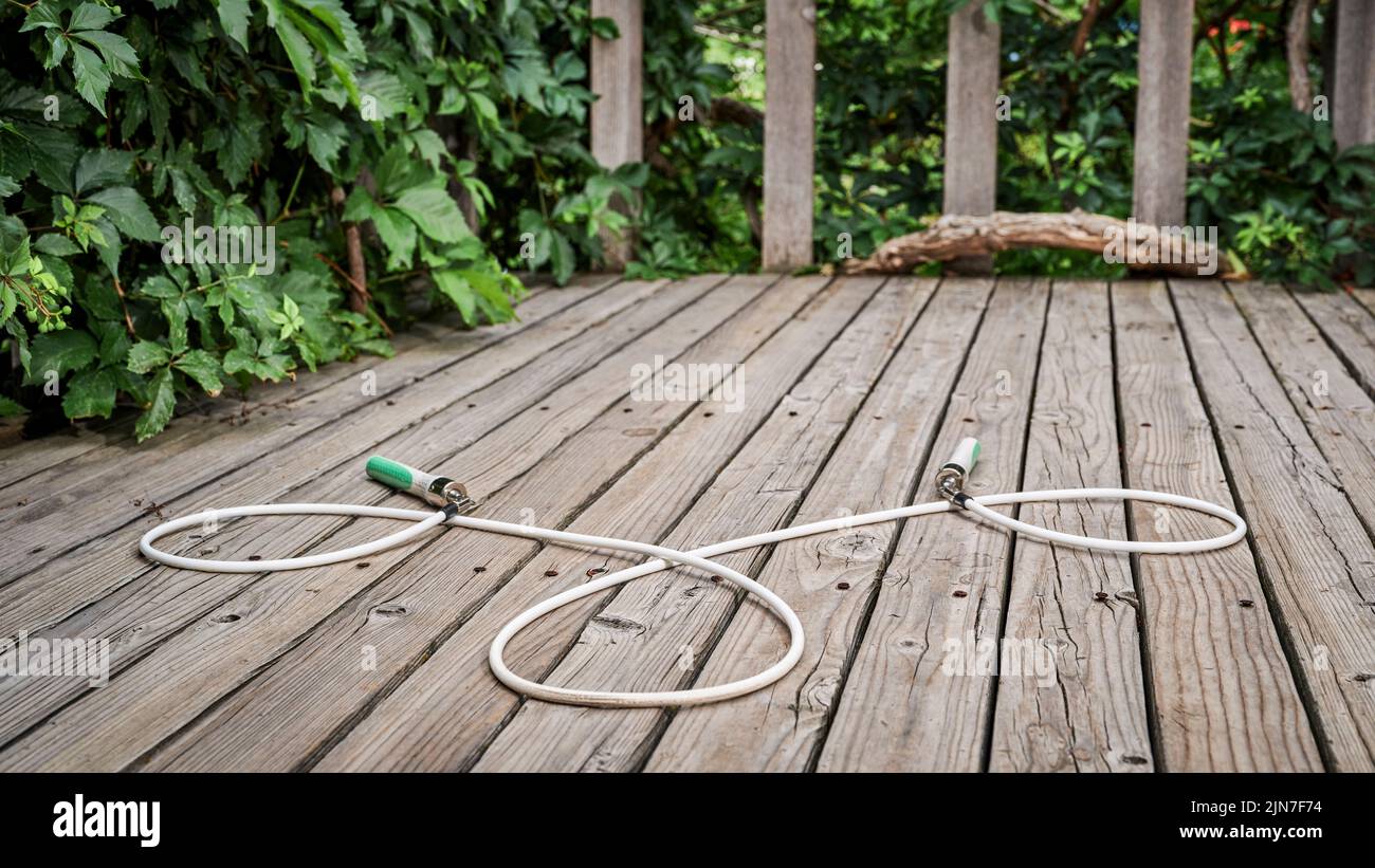 heavy fitness saltar cuerda en rústico, envejecido madera patio trasero cubierta Foto de stock