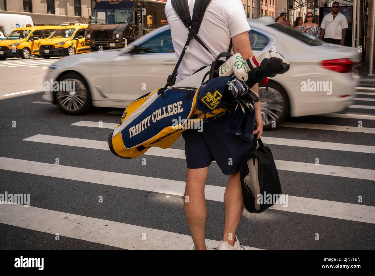 Un golfista camina en Nueva York con su colección de clubs del golf en una bolsa de la marca de Trinity College el sábado, 30 de julio de 2022. (© Richard B. Levine) Foto de stock