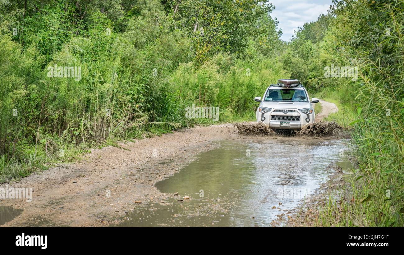 Overton, MO, EE.UU. - 13 de agosto de 2017: Toyota 4Runner SUV (2016 edición Trail) Llevar una tabla de remo está conduciendo a través de charcos de agua en un di Foto de stock