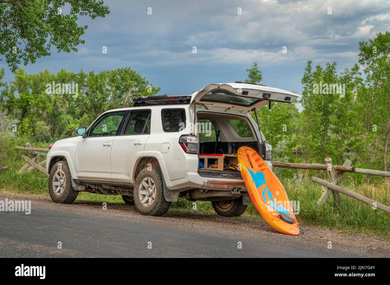 Fort Collins, CO, EE.UU. - 27 de junio de 2022 : Un kayak propenso de Bellyak está siendo cargado en Toyota 4Runner SUV en la orilla de un lago después de una sesión de remo. Foto de stock