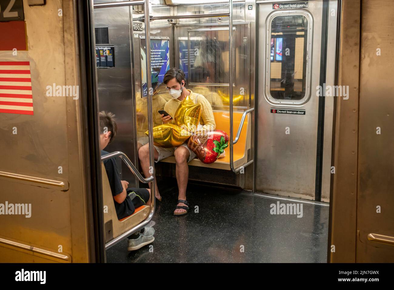 Viajero del metro con globos en el tren “E” de la IND en Nueva York el sábado, 30 de julio de 2022. (© Richard B. Levine) Foto de stock