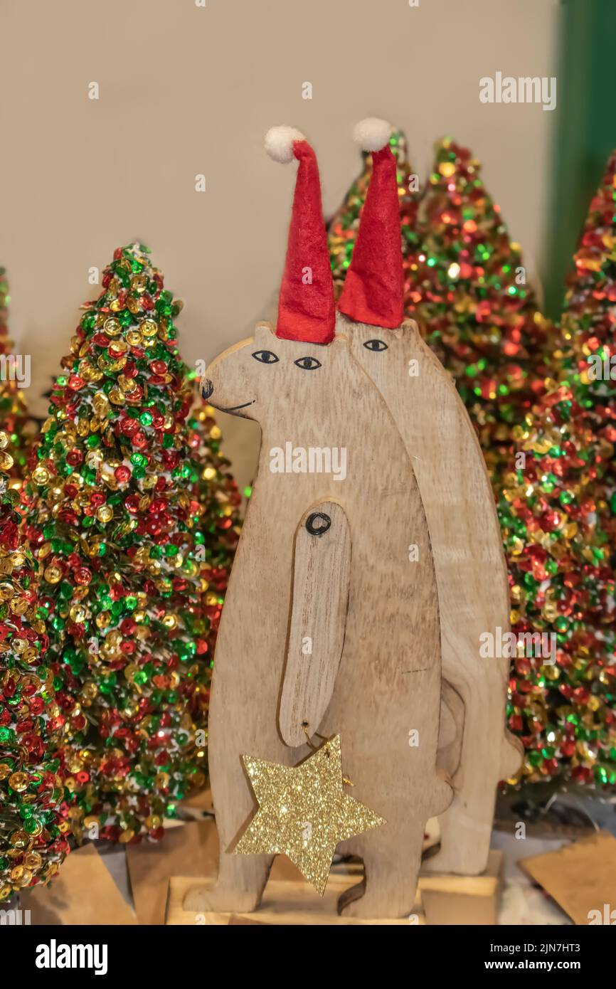Dos osos de madera llevando adornos de Navidad estrellas brillantes delante de los árboles de Navidad bokeh purpurina - enfoque selectivo Foto de stock