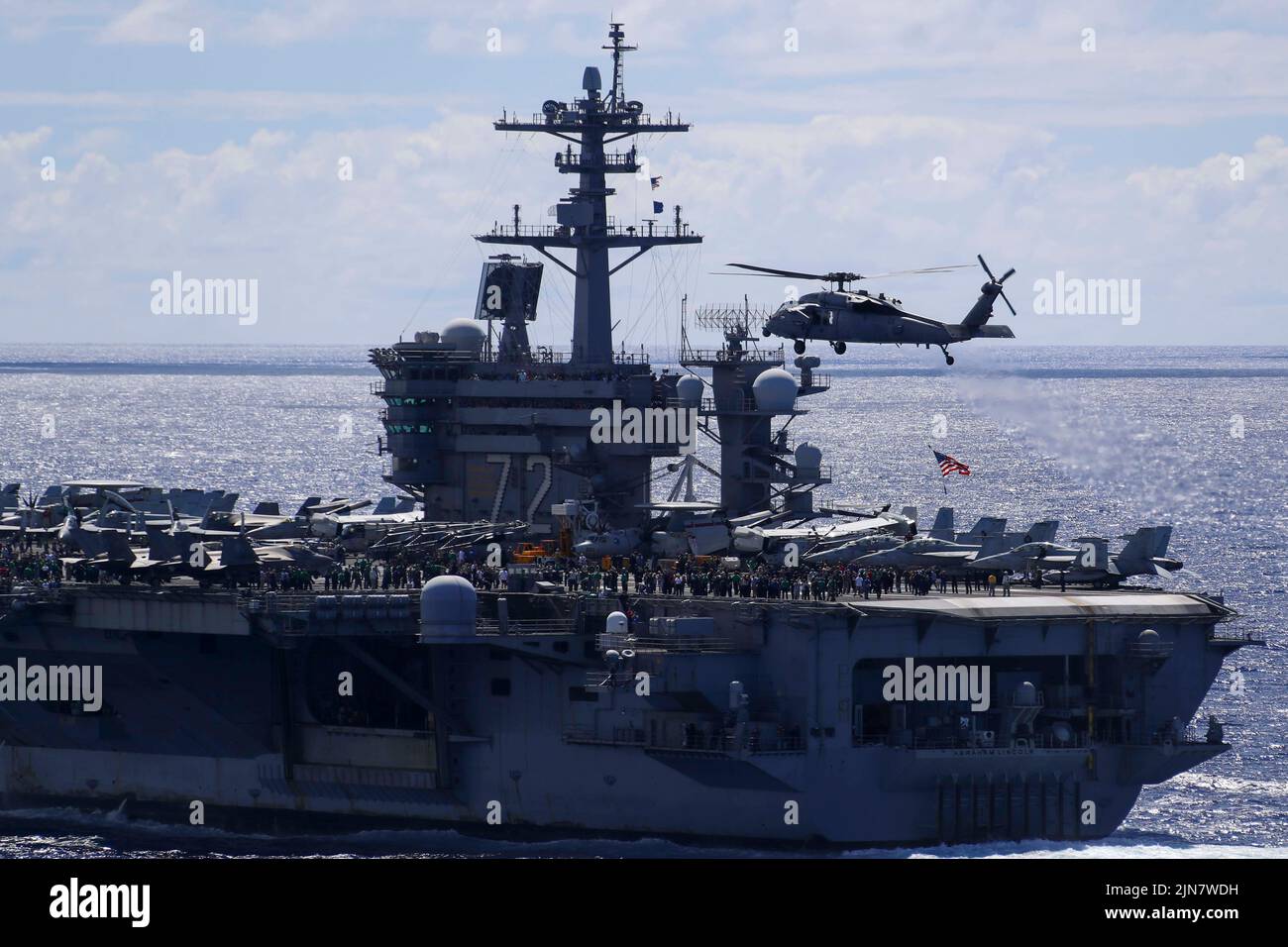 OCÉANO PACÍFICO (7 de agosto de 2022) Los marineros y los huéspedes embarcados observan un helicóptero MH-60s Sea Hawk, asignado a los “Chargers” del Escuadrón de Combate Marino de Helicóptero (HSC) 14, volando por el portaaviones de clase Nimitz USS Abraham Lincoln (CVN 72) durante una demostración de potencia aérea. El Abraham Lincoln Carrier Strike Group está llevando a cabo operaciones rutinarias en la Flota 3rd de los Estados Unidos. (EE. UU Foto de la Marina por el Especialista en Comunicación de Masas 2nd Clase Jeffrey F. Yale) Foto de stock