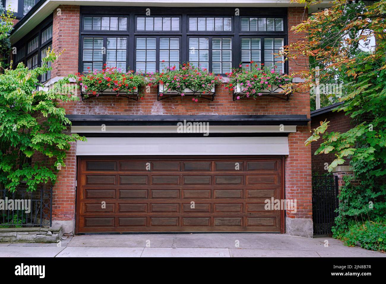 Casa con garaje para dos coches con puerta de grano de madera en planta baja y una habitación encima Foto de stock