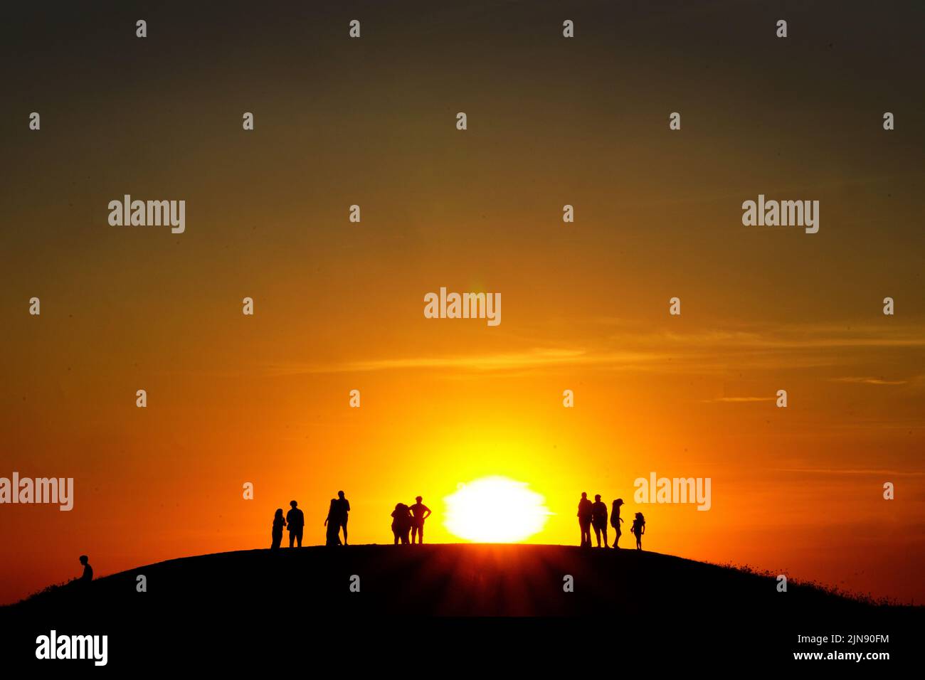 Grupos de personas ven la puesta de sol desde una colina en Ealing, al oeste de Londres, mientras continúa un verano de prohibiciones de tubos de escape y advertencias de incendios, con una alerta de salud por calor que se está implantando en gran parte del país. Fecha de la foto: Martes 9 de agosto de 2022. Foto de stock