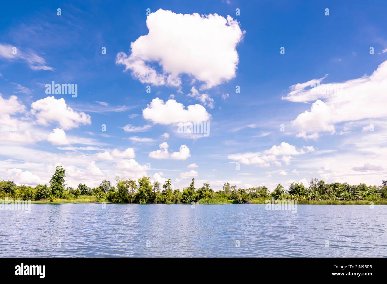 lago estanque contra árboles verdes cerca del cielo azul con nubes. Foto de stock