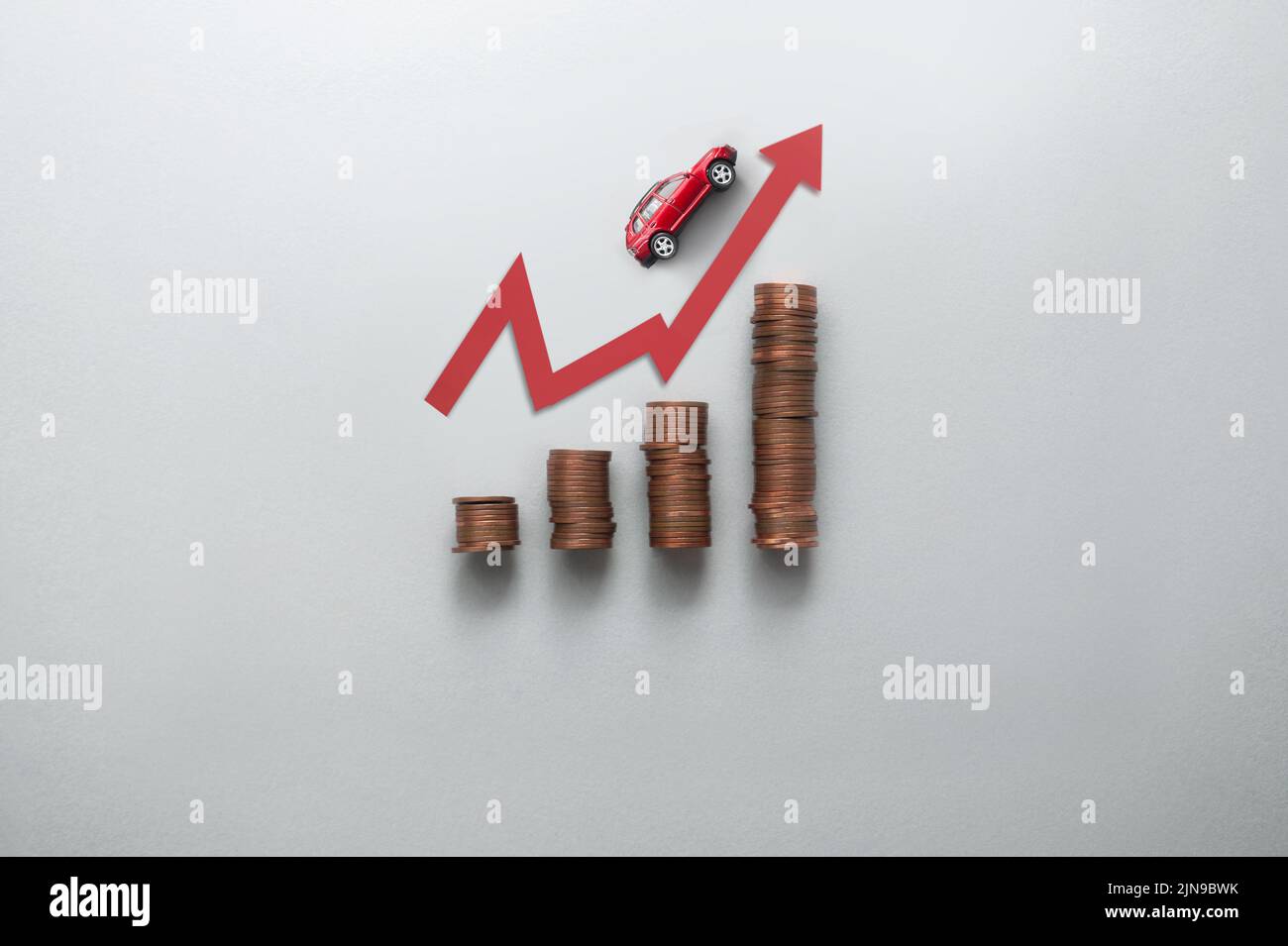 El aumento del concepto de precio de la gasolina, las pilas de gráfico de negocios de monedas con coche de juguete que se mueve hacia arriba a lo largo de la flecha Foto de stock