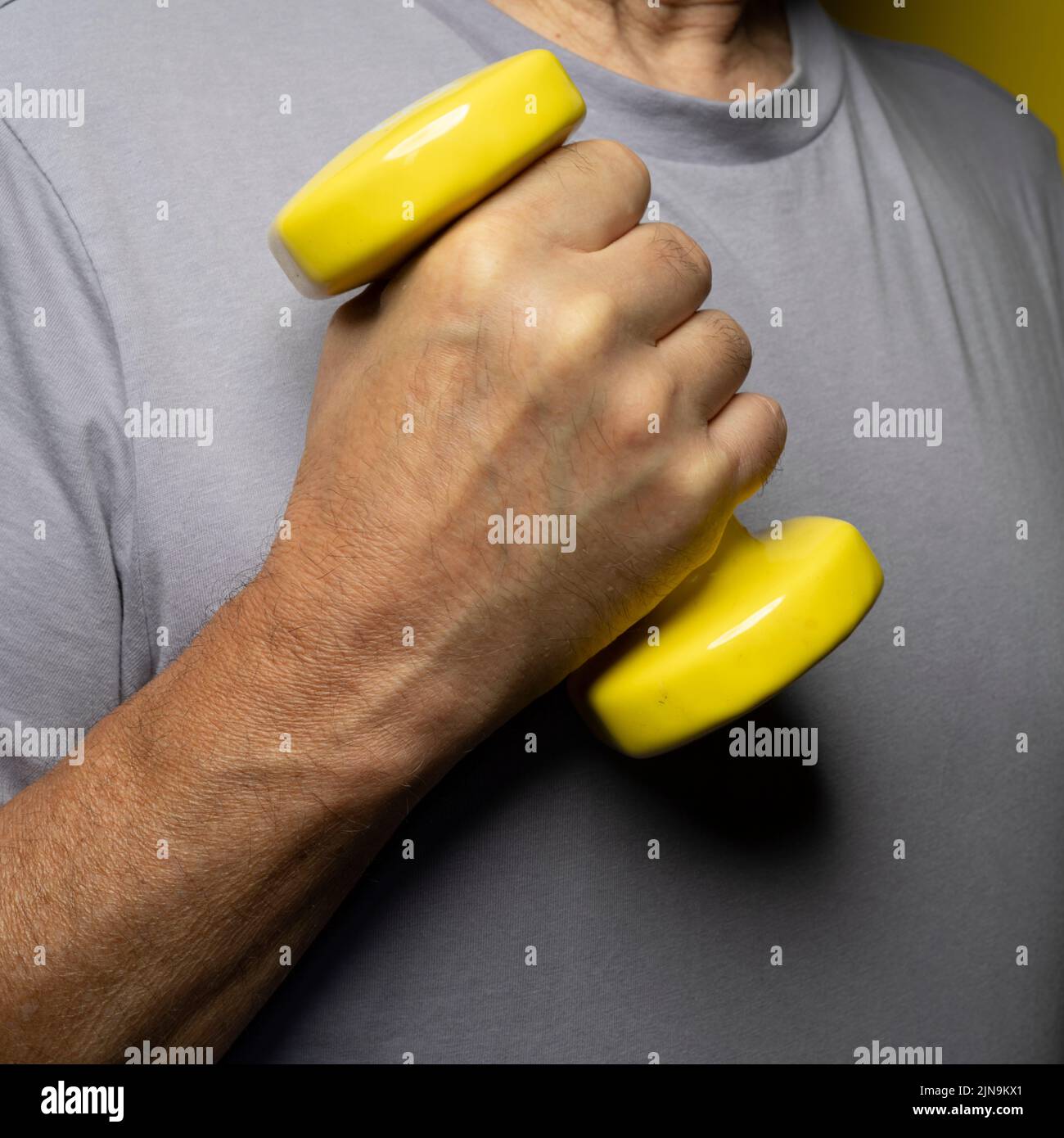 pesas gimnásticas amarillas en la mano Foto de stock