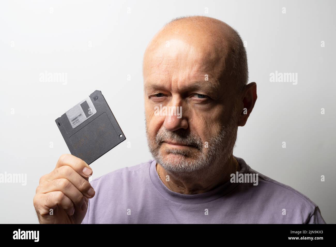 un hombre con un viejo disquete en la mano Foto de stock