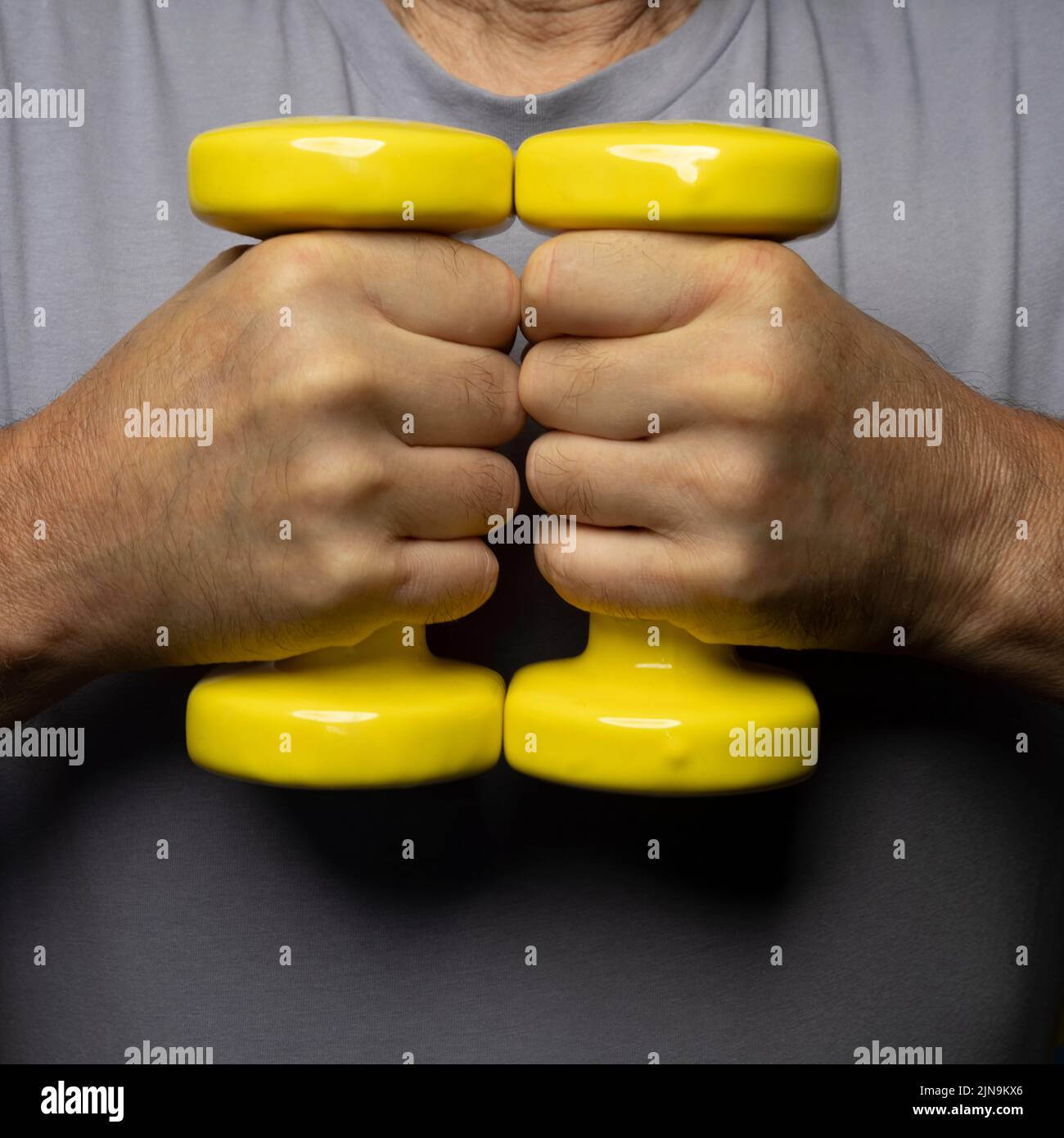 pesas gimnásticas amarillas en la mano Foto de stock