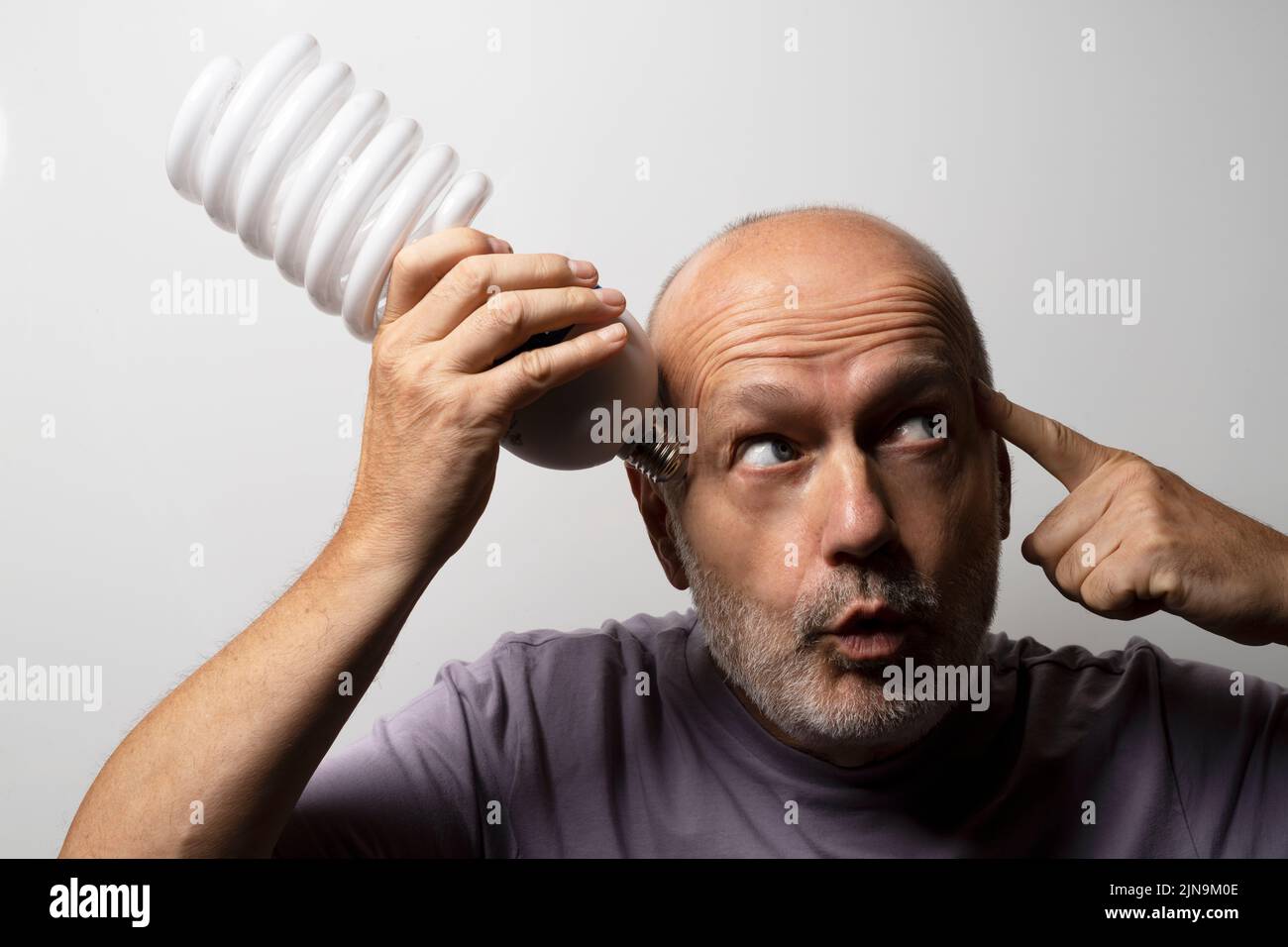 el concepto de idea con una enorme bombilla electrónica de bajo consumo en la mano de un hombre pensante Foto de stock