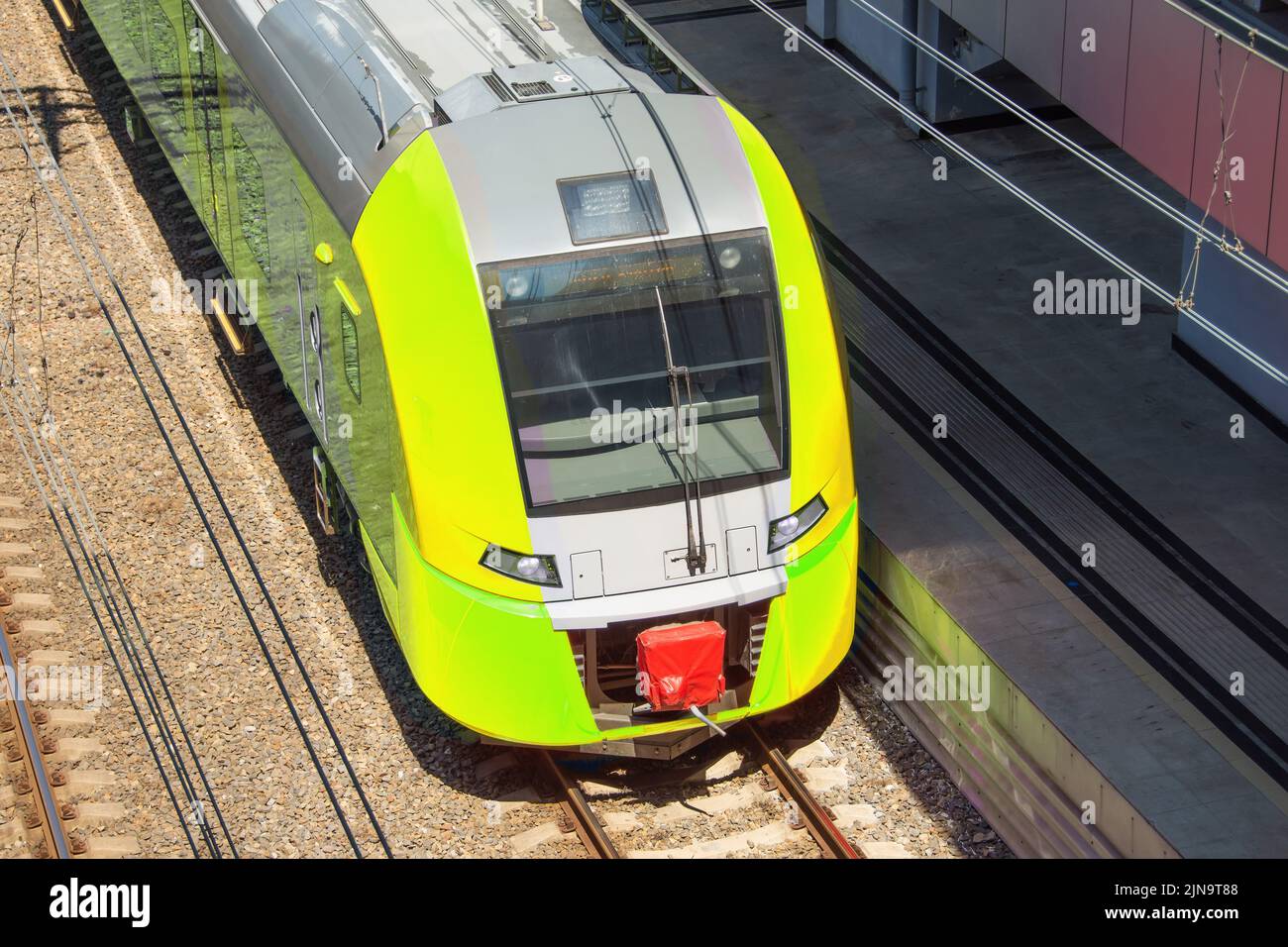 Tren eléctrico amarillo suburbano en la plataforma de pasajeros de la estación Foto de stock