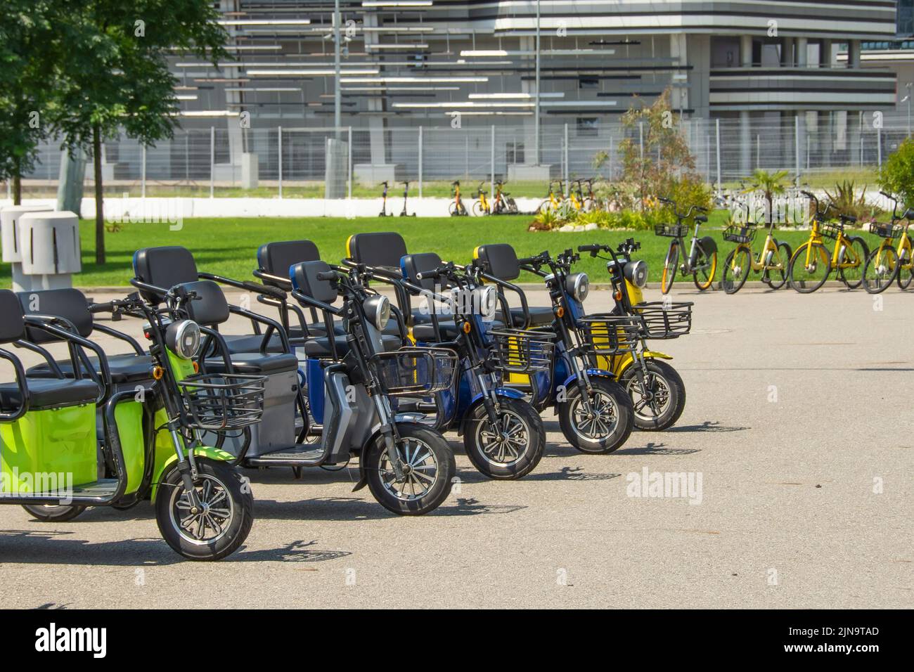 Scooters eléctricos, ciclomotores de tres plazas en el aparcamiento para alquilar y desplazarse por la ciudad Foto de stock