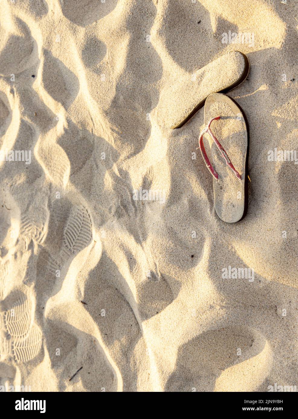todavía la vida de chanclas dejadas atrás en una playa oceánica Foto de stock