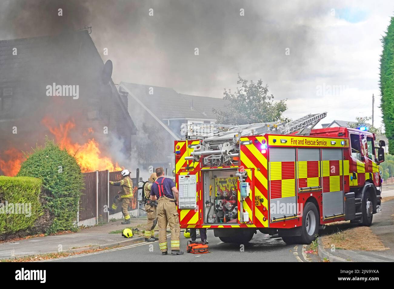 Servicios de bomberos y rescate de Essex bomberos asistentes a la quema de casa en incendio con brigada de bomberos licitación en asistencia Inglaterra Reino Unido Foto de stock