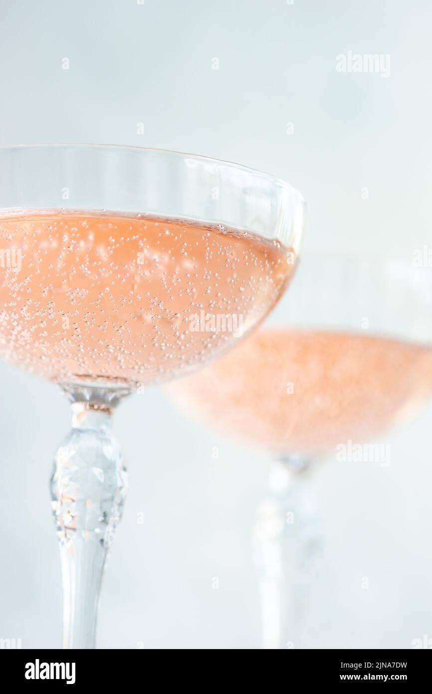 Vino espumoso rosado o champán en copas de cristal sobre fondo blanco de hormigón en días soleados Foto de stock
