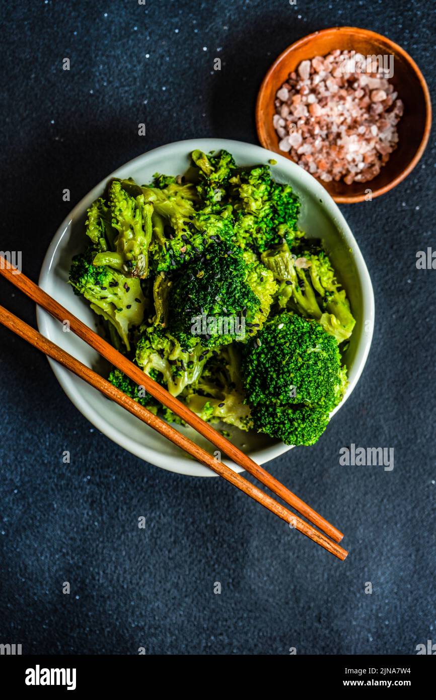 Brócoli a la parrilla con semillas de sésamo en el recipiente sobre una mesa de hormigón Foto de stock