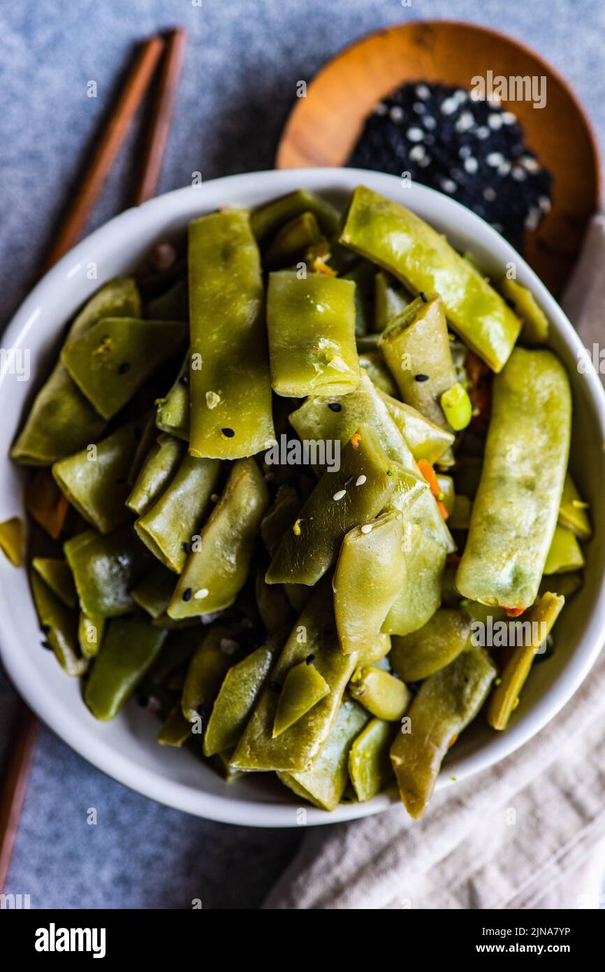 Judías verdes con semillas de sésamo en el recipiente sobre una mesa de hormigón Foto de stock