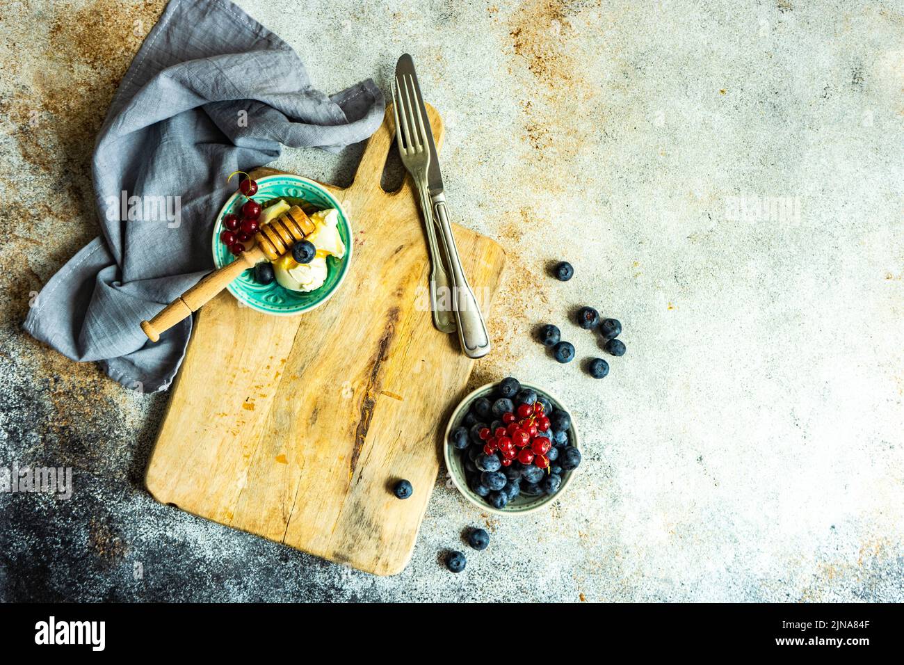 Postre saludable con bayas orgánicas frescas y crema agria sobre tabla de cortar Foto de stock