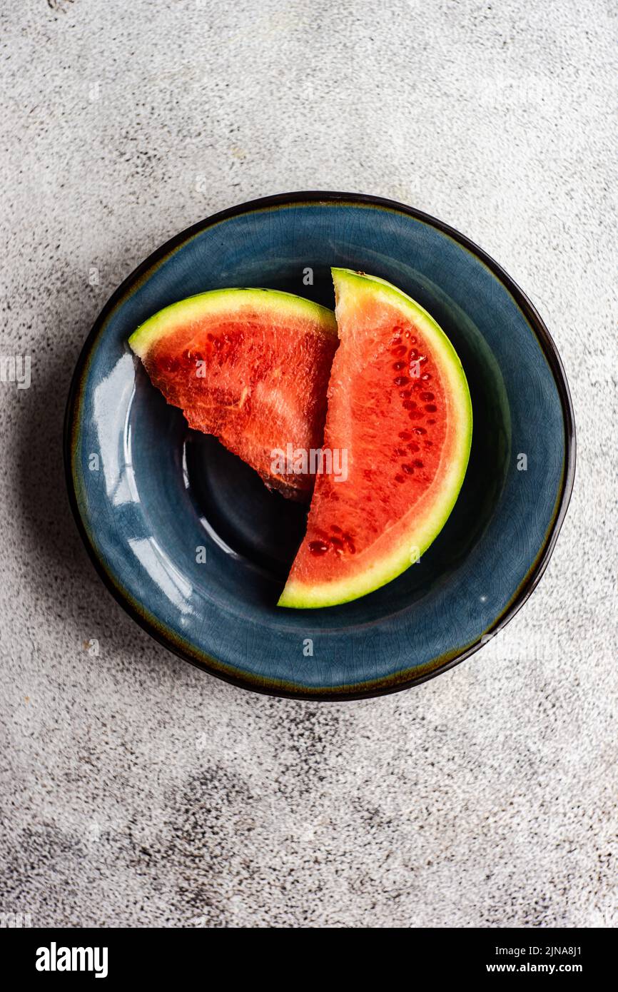 Postre de verano sano con rebanadas de sandía servido en el cuenco de cerámica sobre una mesa de hormigón Foto de stock