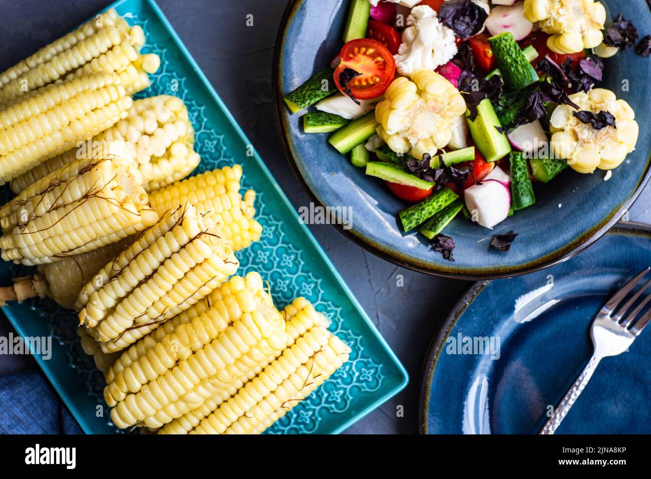 Ensalada de verduras saludables con maíz hervido servido en el cuenco azul profundo Foto de stock