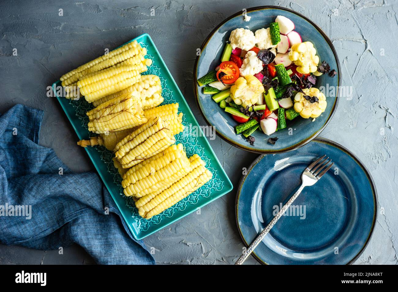 Ensalada de verduras saludables con maíz hervido servido en el cuenco azul profundo Foto de stock
