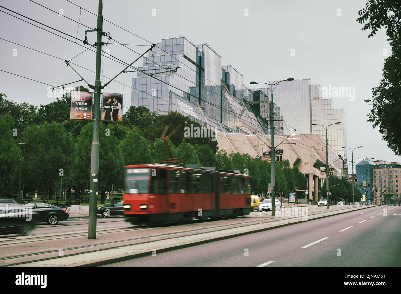 Nueva escena callejera de Belgrado con modernos edificios de vidrio y tranvía rojo en movimiento borroso, Serbia Foto de stock