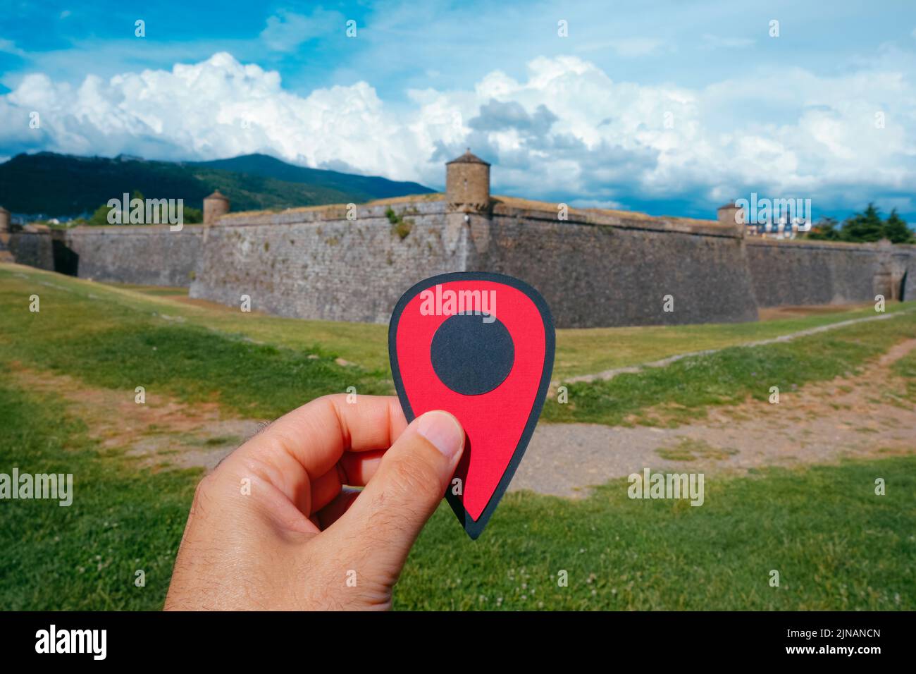 Primer plano de la mano de un hombre que sostiene un marcador rojo que señala la Ciudadela de Jaca, en Jaca, provincia de Huesca, Aragón, España, en un soleado verano Foto de stock