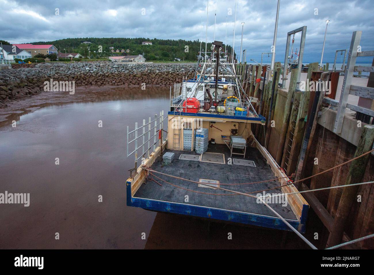 Los barcos de pesca de langosta se sientan en el fondo del océano en el puerto de Alma, New Brunswick el miércoles 6 de julio de 2022. Foto de stock
