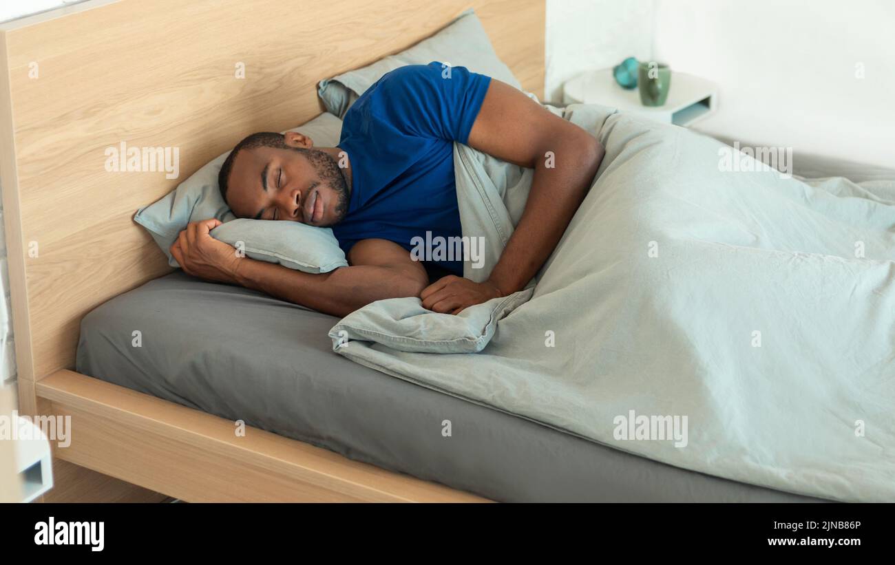 Hombre afroamericano durmiendo en casa acostado en la cama interior Foto de stock