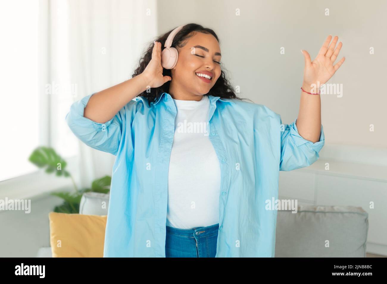 Mujer afroamericana usando auriculares escuchando música bailando en casa Foto de stock