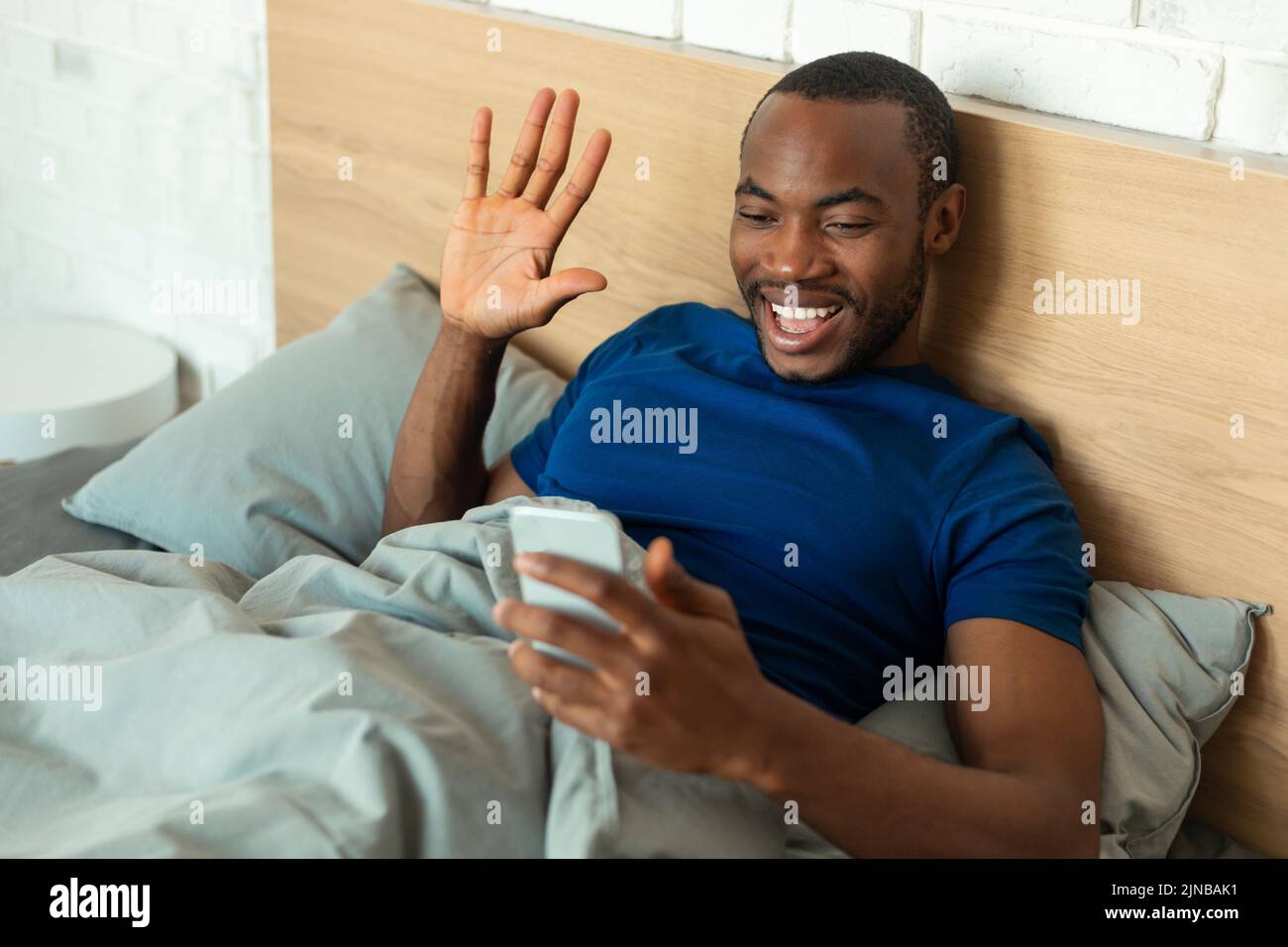 Black Guy agitando el teléfono haciendo videollamada en la habitación Foto de stock