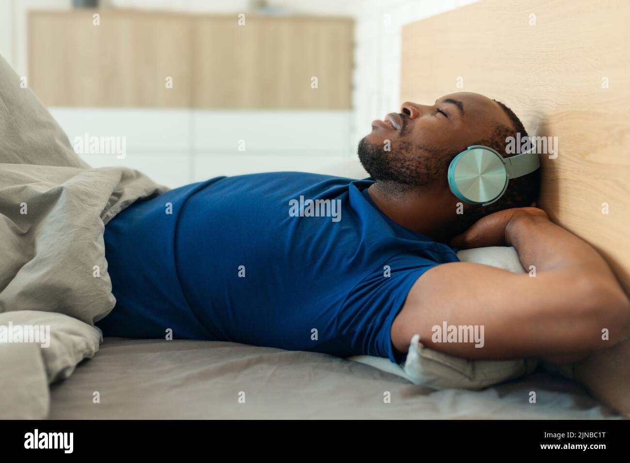 Hombre Negro Llevando Auriculares Escuchando Música Relajante en la Habitación Foto de stock