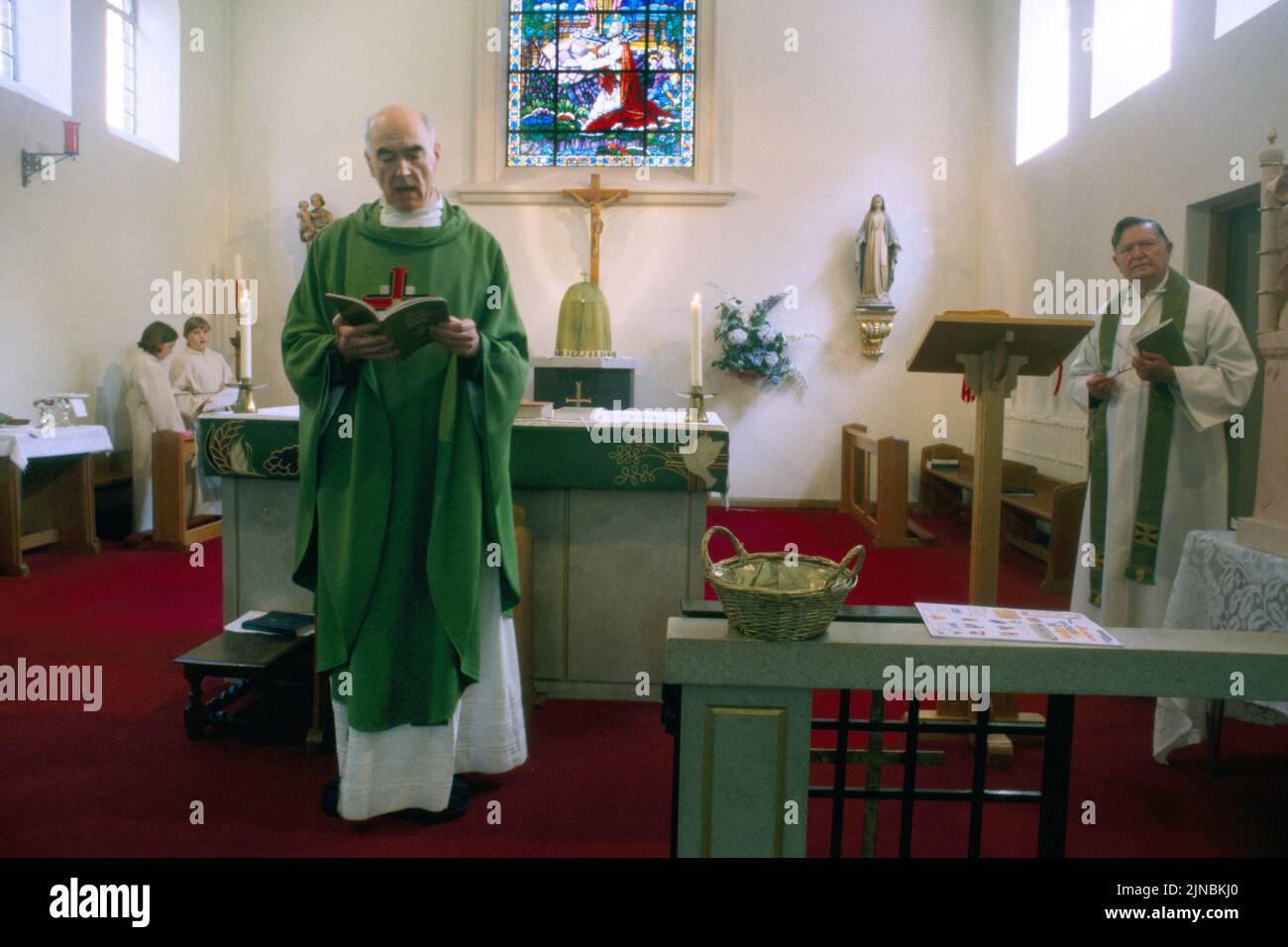 Sacerdotes leyendo Escrituras por Altar en la Iglesia Católica de St Ann Kingston Londres Inglaterra Foto de stock