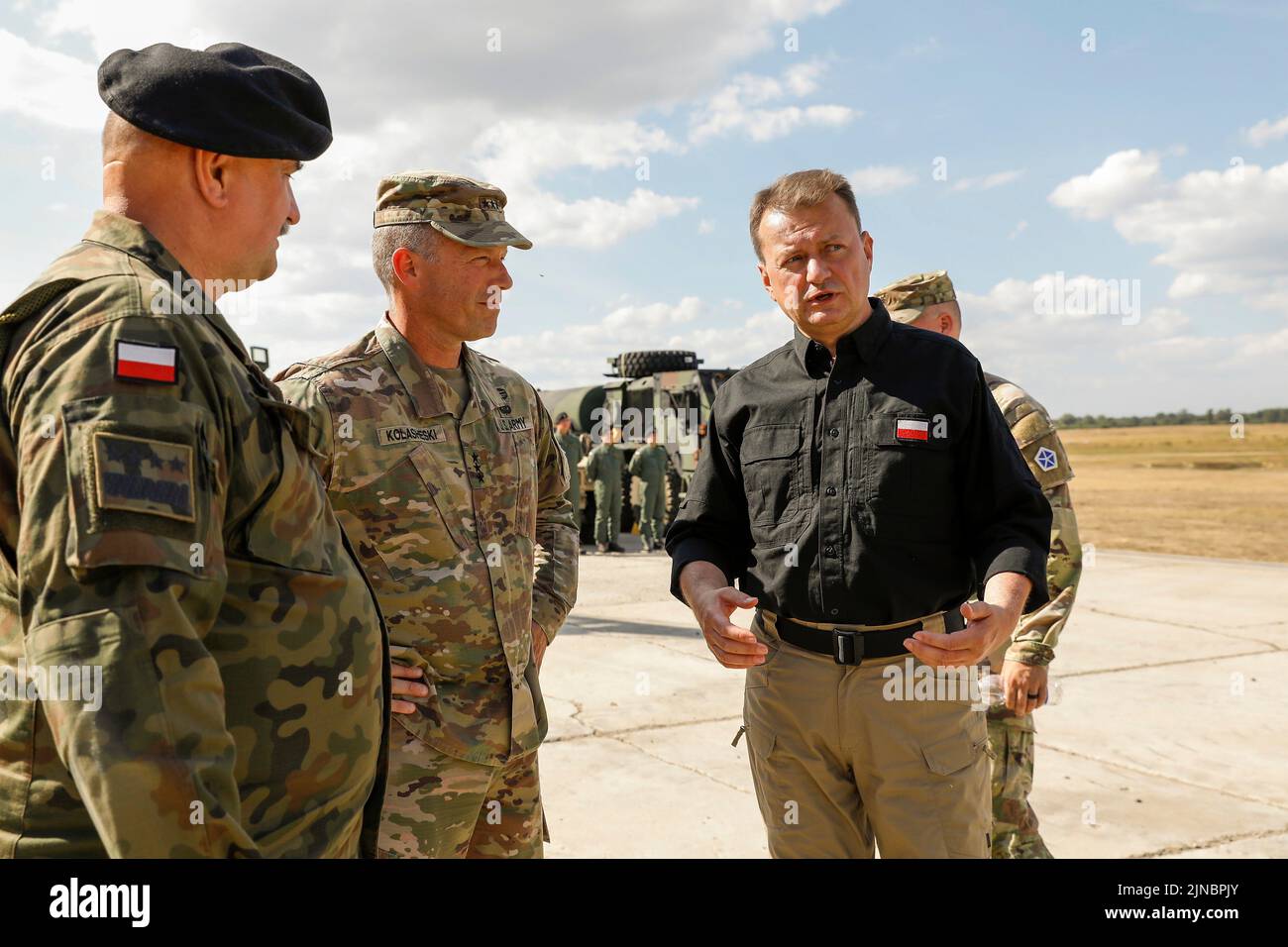 Biedrusko, Polonia. 10th de Ago de 2022. El Ministro de Defensa de Polonia, Mariusz Blaszczak, a la derecha, habla con el Teniente General John Kolasheski del Ejército de los Estados Unidos, al mando del V Cuerpo, y con el General de las Fuerzas Terrestres de Polonia Jaroslaw Mika, a la izquierda, durante la ceremonia de apertura de la Academia de Entrenamiento de Tanques Abrams en el Centro de Entrenamiento de las Fuerzas Terrestres el 10 de agosto de 2022 en Biedrusko, Polonia. La Academia de Entrenamiento de Tanques de Abrams fue establecida para enseñar a los tripulantes polacos de tanques sobre operaciones, tácticas y mantenimiento del tanque de batalla principal de Abrams de M1. Crédito: SPC. Hassani Ribera/Ejército de los Estados Unidos/Alamy Live News Foto de stock