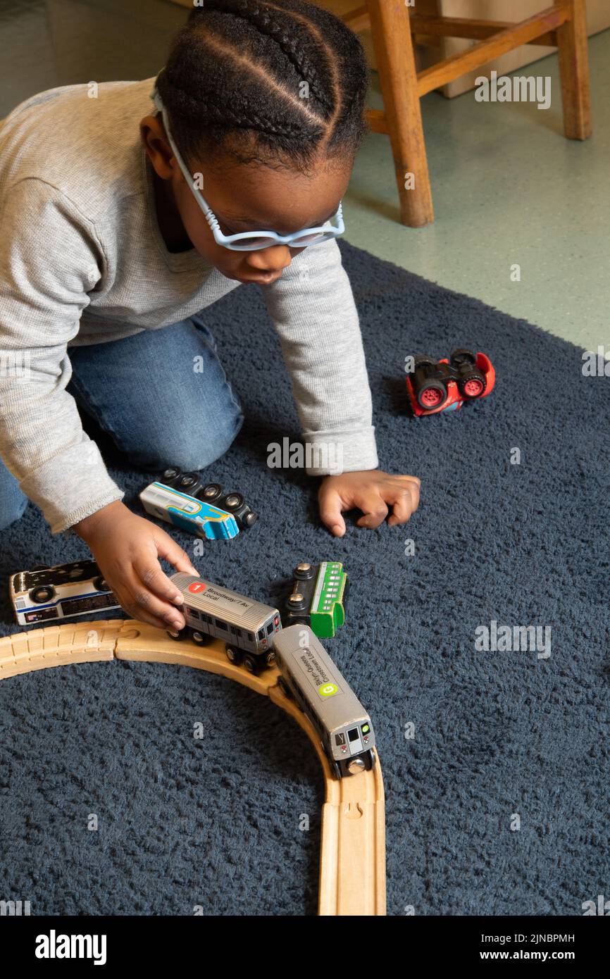 Educación Cuidado Infantil Preescolar Niño de 2-3 años jugando con el tren, usando gafas Foto de stock